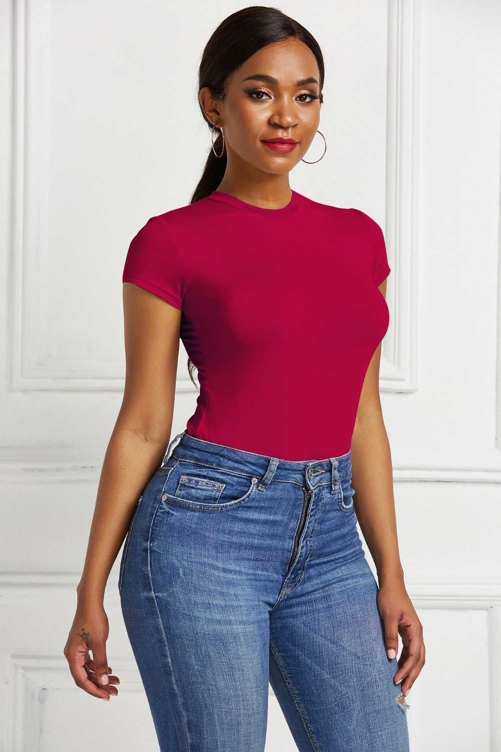 Sculpted crew neck bodysuit in burgundy with short sleeves, styled with blue jeans.