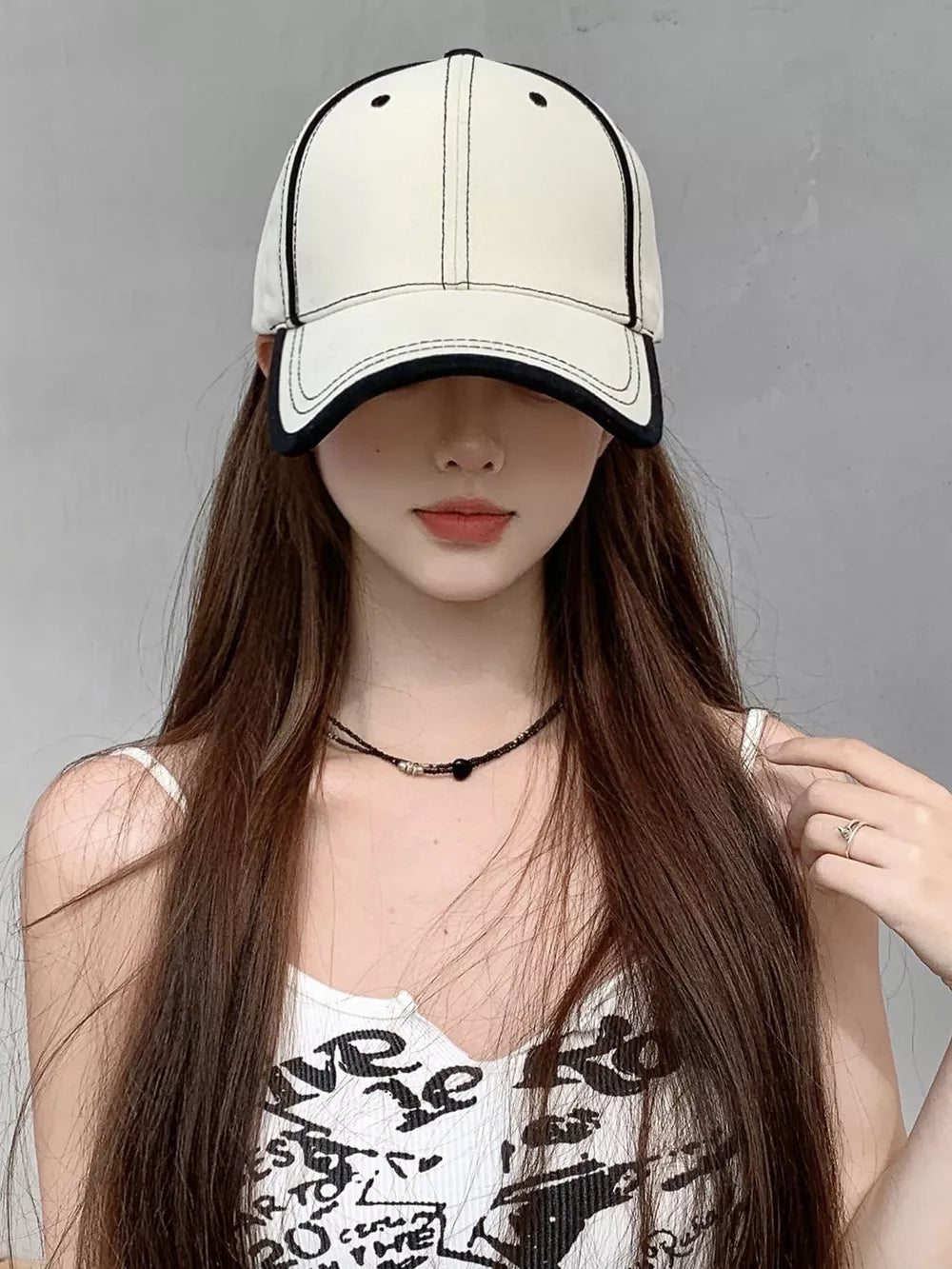Cream white cotton baseball cap with black contrast stitching and brim trim.