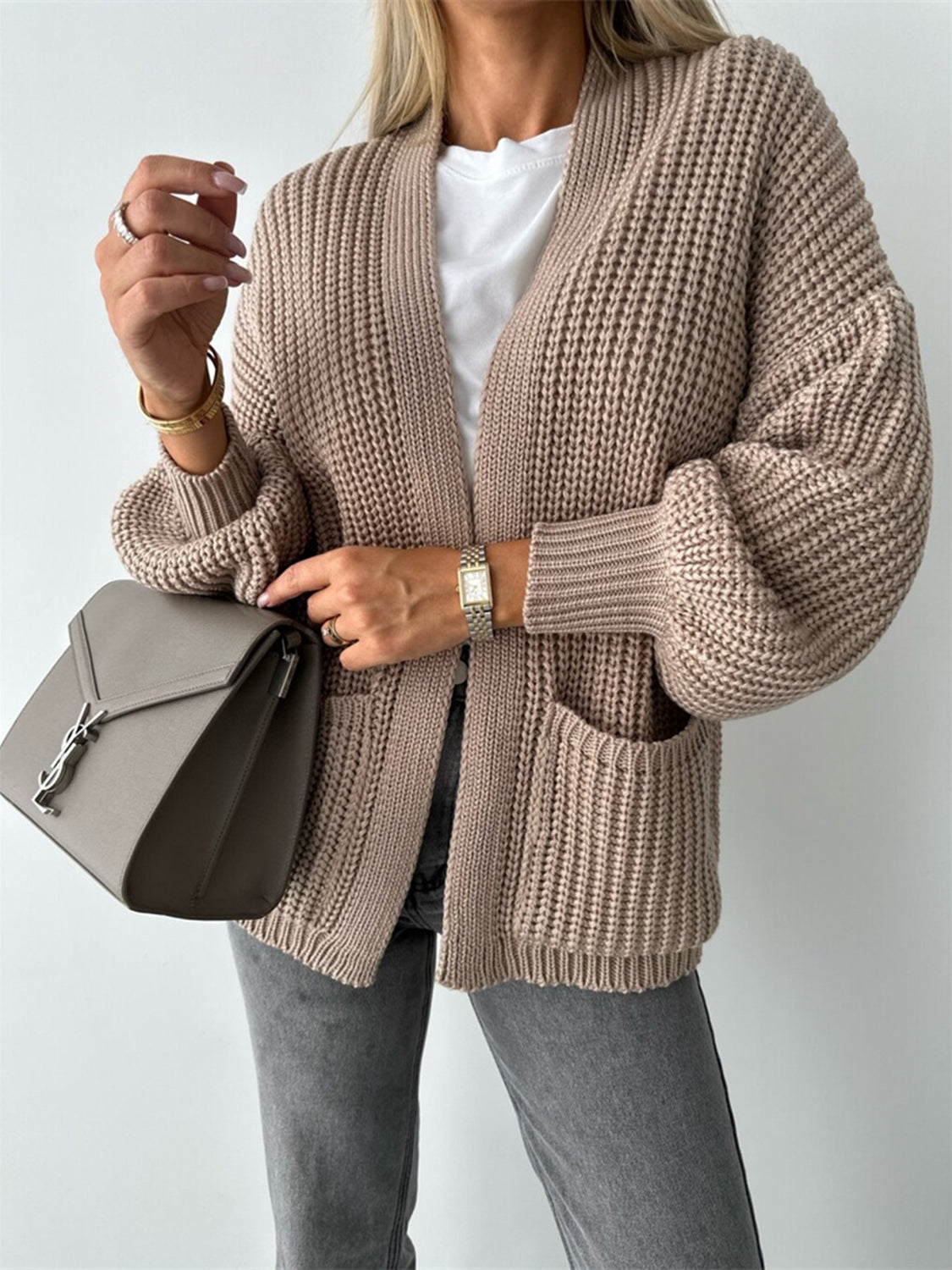 Beige textured knit cardigan with puff sleeves and front pockets.