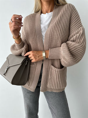 Beige textured knit cardigan with puff sleeves and front pockets.