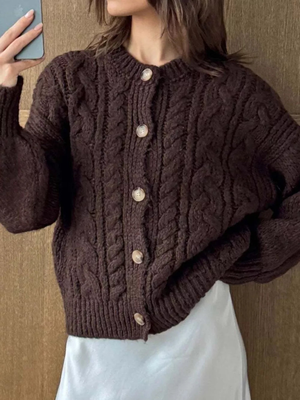 Brown cable-knit button-down cardigan with round neckline and wooden buttons.