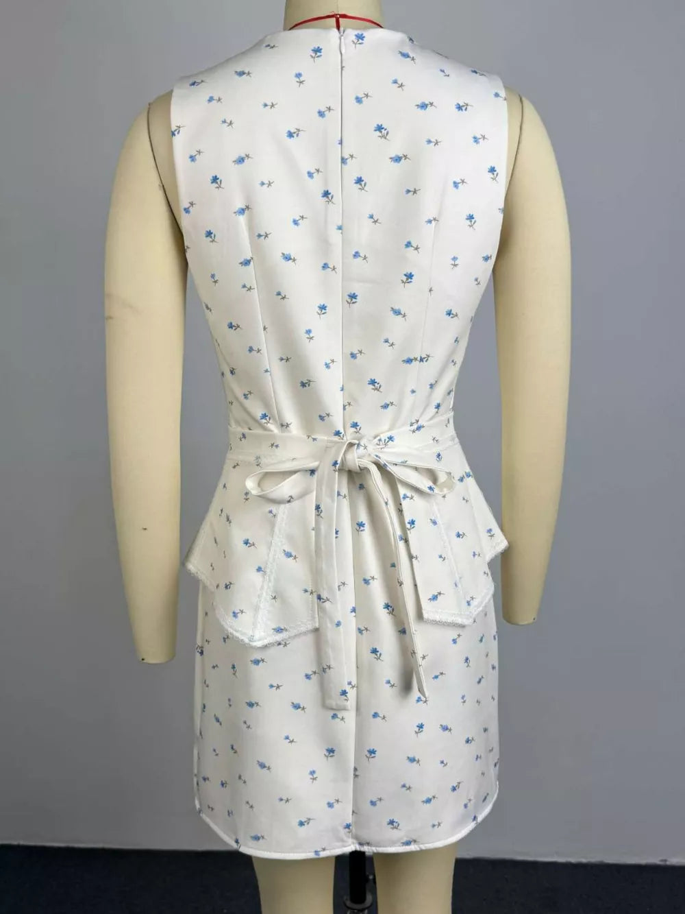 Floral peplum set in white with blue flowers, featuring a tie waist and ruffled hem.