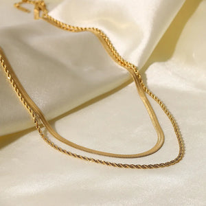 Gold serpentine and rope chain necklaces layered on satin fabric
