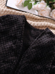 Children's black fuzzy cardigan with textured fabric detail.