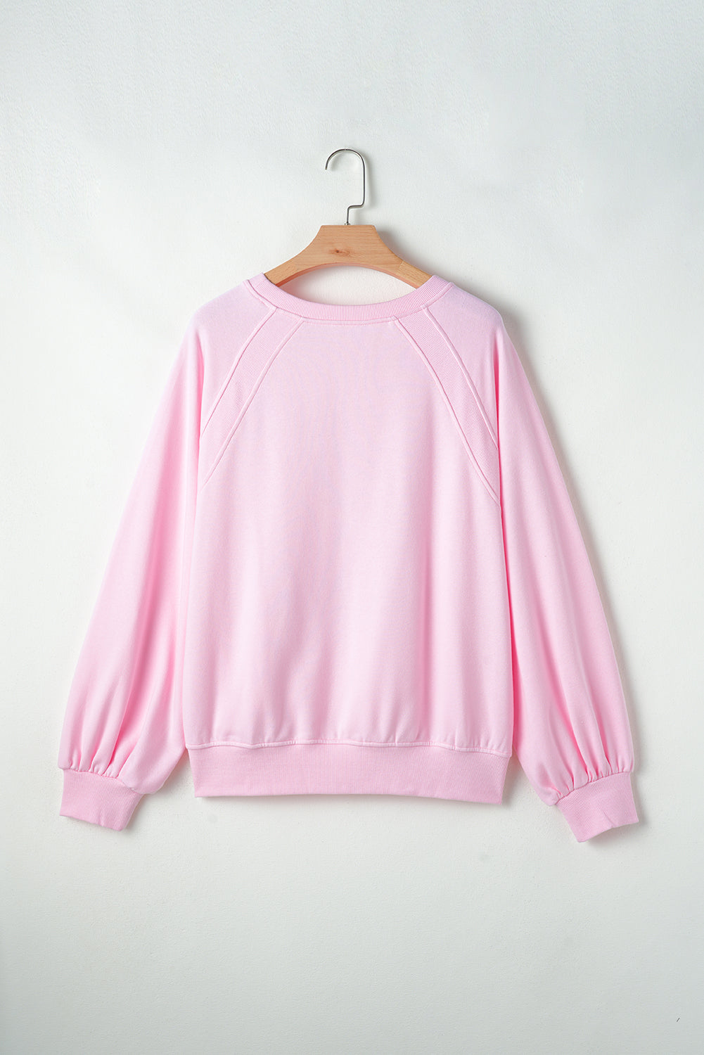Blush pink sweatshirt with crew neck, raglan sleeves, and cinched cuffs.