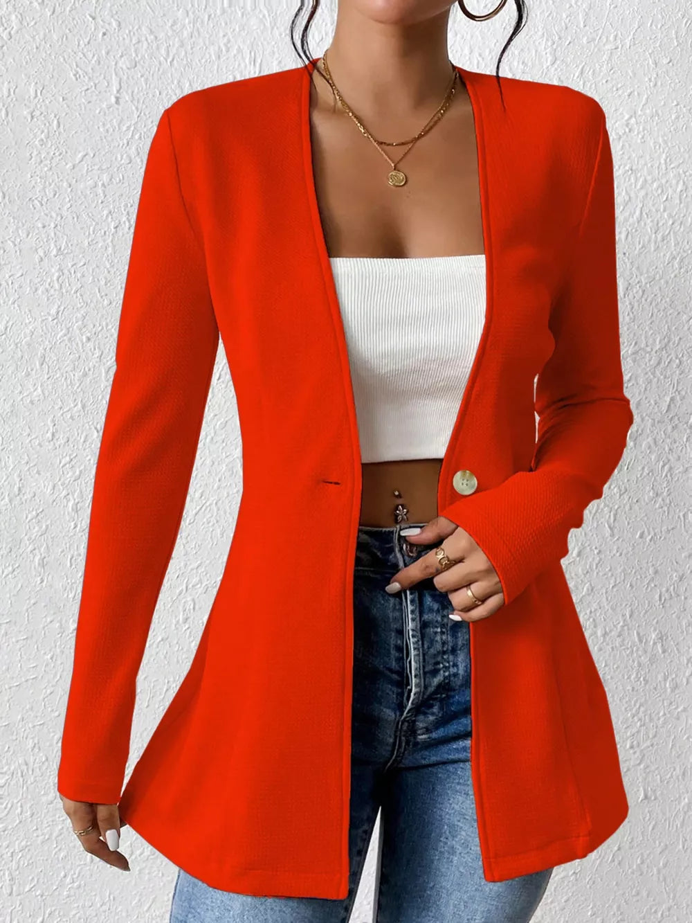 Red single-button blazer with tailored fit and long sleeves, styled with a white top and jeans.