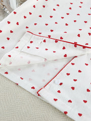 White cotton pajama set with red heart pattern and red piping detail.
