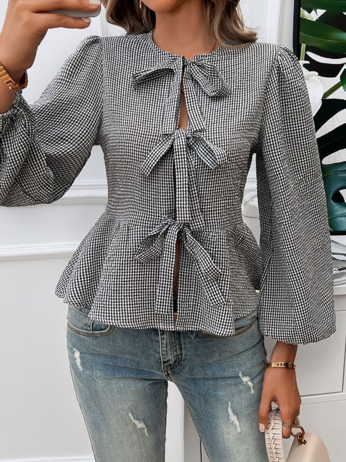Black gingham peplum blouse with puff sleeves and three bow details.