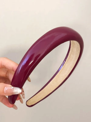 Glossy padded headband in deep purple with a beige lining.