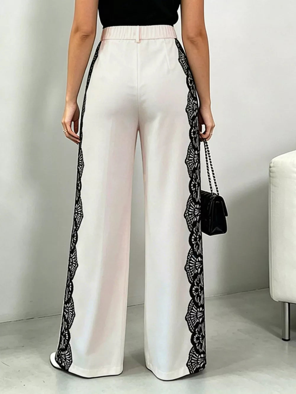 Maternity pants in white with black lace trim down the sides, high-waisted, wide leg