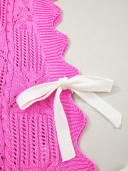 Chic pink openwork knit sweater vest with cable knit detail and white tie closure.