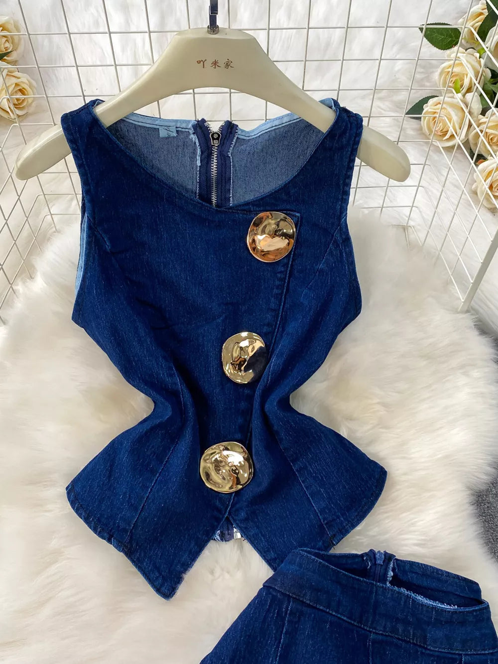 Dark blue cotton denim vest with asymmetrical gold buttons and zipper detail.