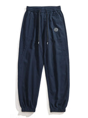 Navy blue relaxed fit joggers with drawstring and elastic cuffs, featuring a circular mountain logo patch.
