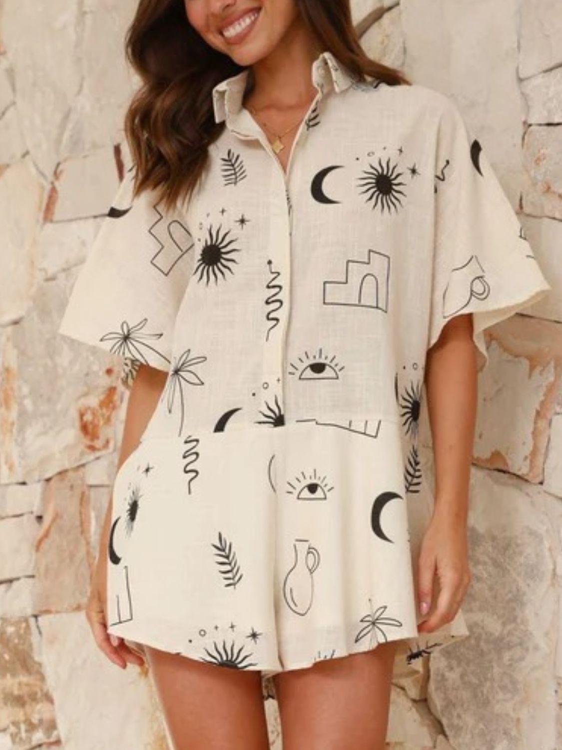 Beige linen romper with celestial print, short sleeves, collared neckline, and button front.