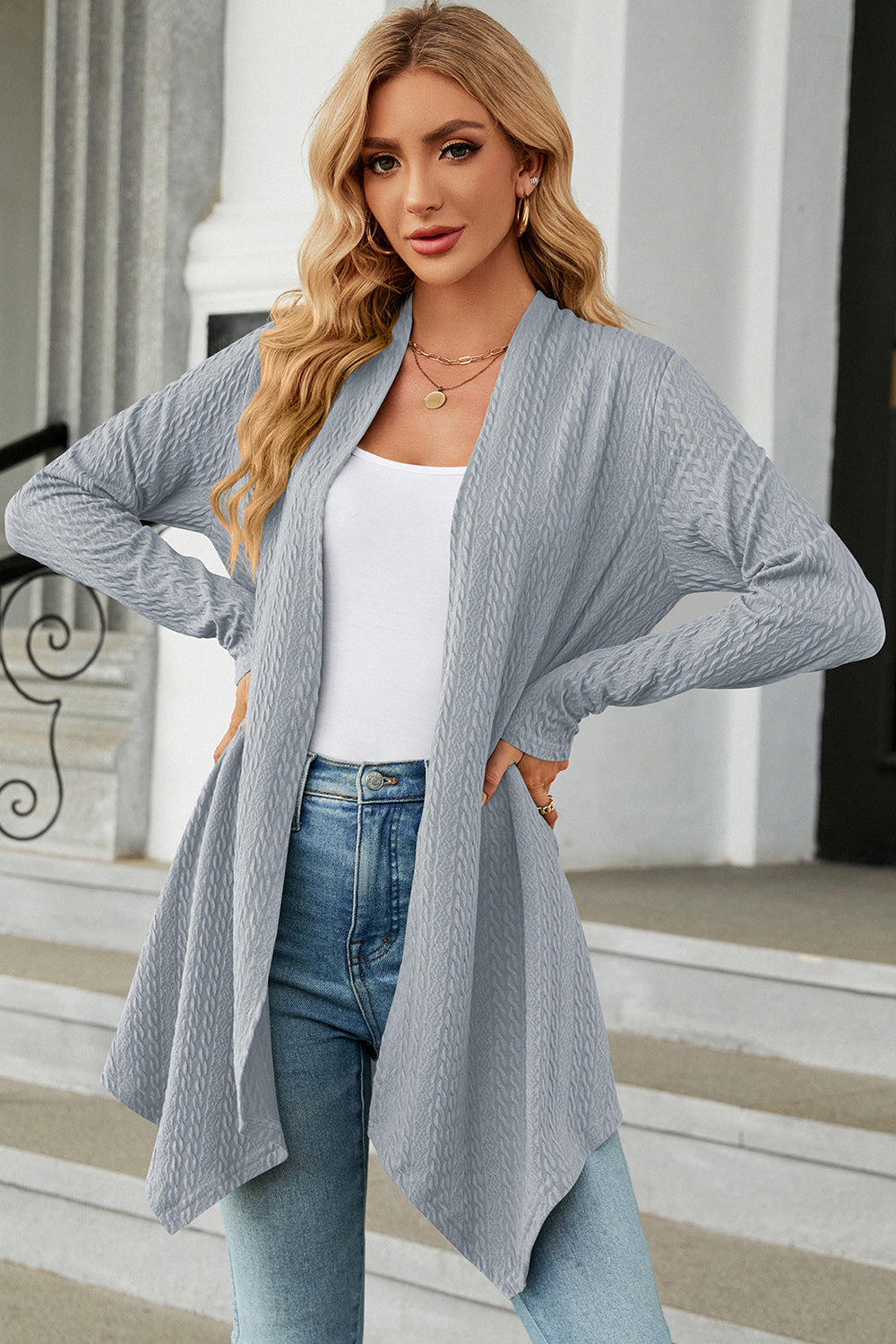 Light blue textured knit cardigan with asymmetrical drape front and long sleeves.