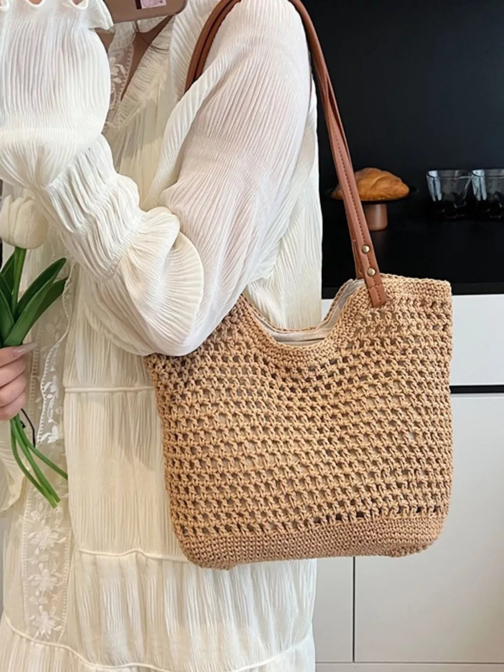 Artisan woven straw shoulder bag in beige with leather straps.