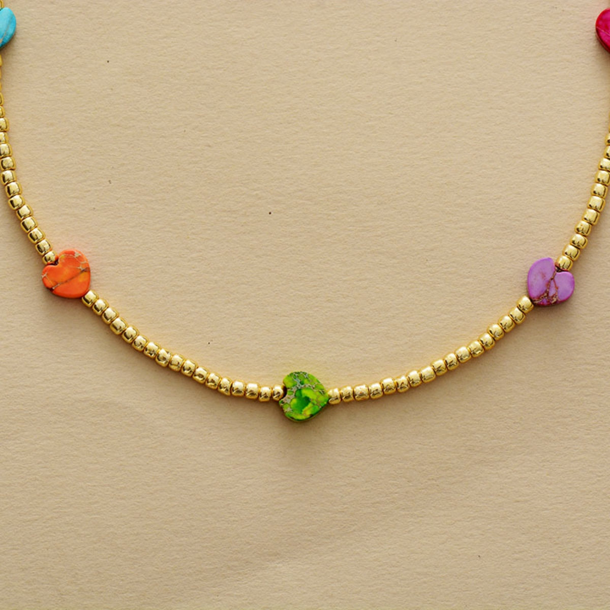 Gold beaded necklace with multicolor heart charms