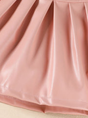 Pink faux leather baby skirt with pleats and a stitched hem detail.