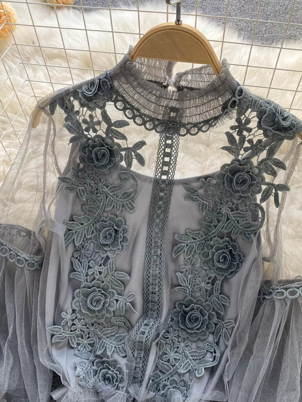 Gray lace blouse with floral embroidery and sheer sleeves.