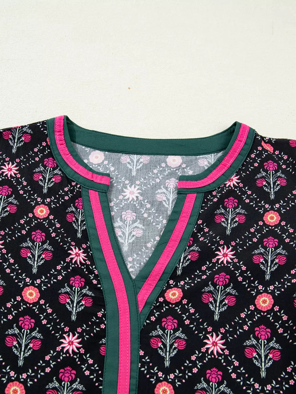Black floral print cotton blouse with contrast green and pink trim at the V-neck.