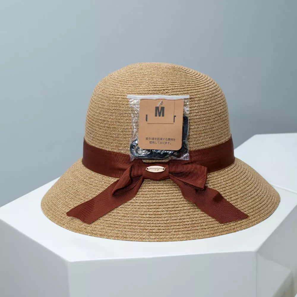 Straw bucket hat in Dust Storm with downturned brim and brown ribbon detail.