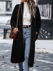 Black teddy coat with contrast trim detailing and open front, worn with jeans.