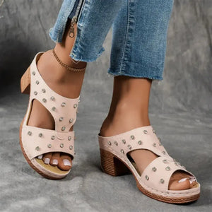 Blush pink studded cutout platform mules with open toe and block heel.