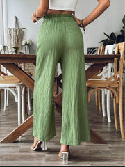 Green textured gauze palazzo trousers with a ruffled waist and wide legs.
