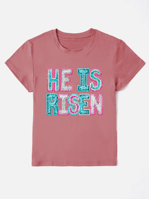 Dusty pink crewneck t-shirt with sequin-textured "He Is Risen" graphic.