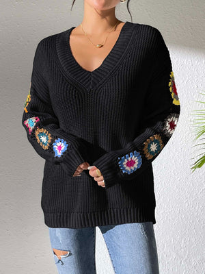 Black v-neck knit sweater with colorful granny square details on sleeves.
