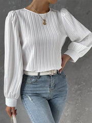 White pleated blouse with gathered shoulders and long sleeves.