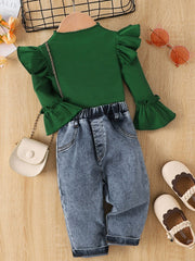 Green ribbed top with ruffle sleeves and bell cuffs paired with denim jeans with elastic waistband.