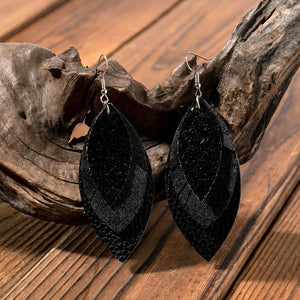 Layered black faux leather statement earrings with textured detail.