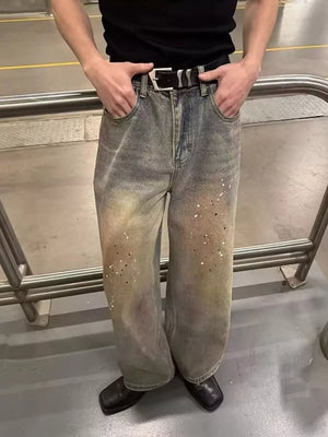 Vintage wash distressed wide-leg jeans with paint splatter detail and a black belt.