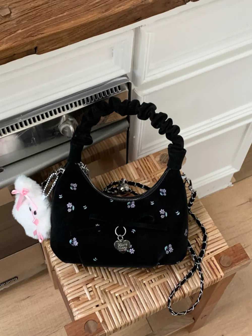 Black ruched mini crossbody bag with floral embroidery and bow charm
