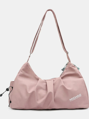 Dusty pink gathered pleat crossbody bag with adjustable strap and side drawstring pocket.