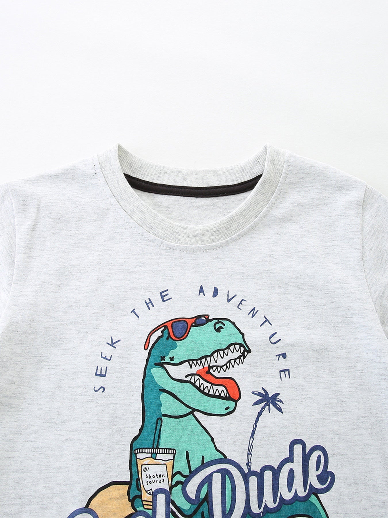 Light grey cotton t-shirt with a graphic of a cool dinosaur wearing sunglasses and holding a drink.