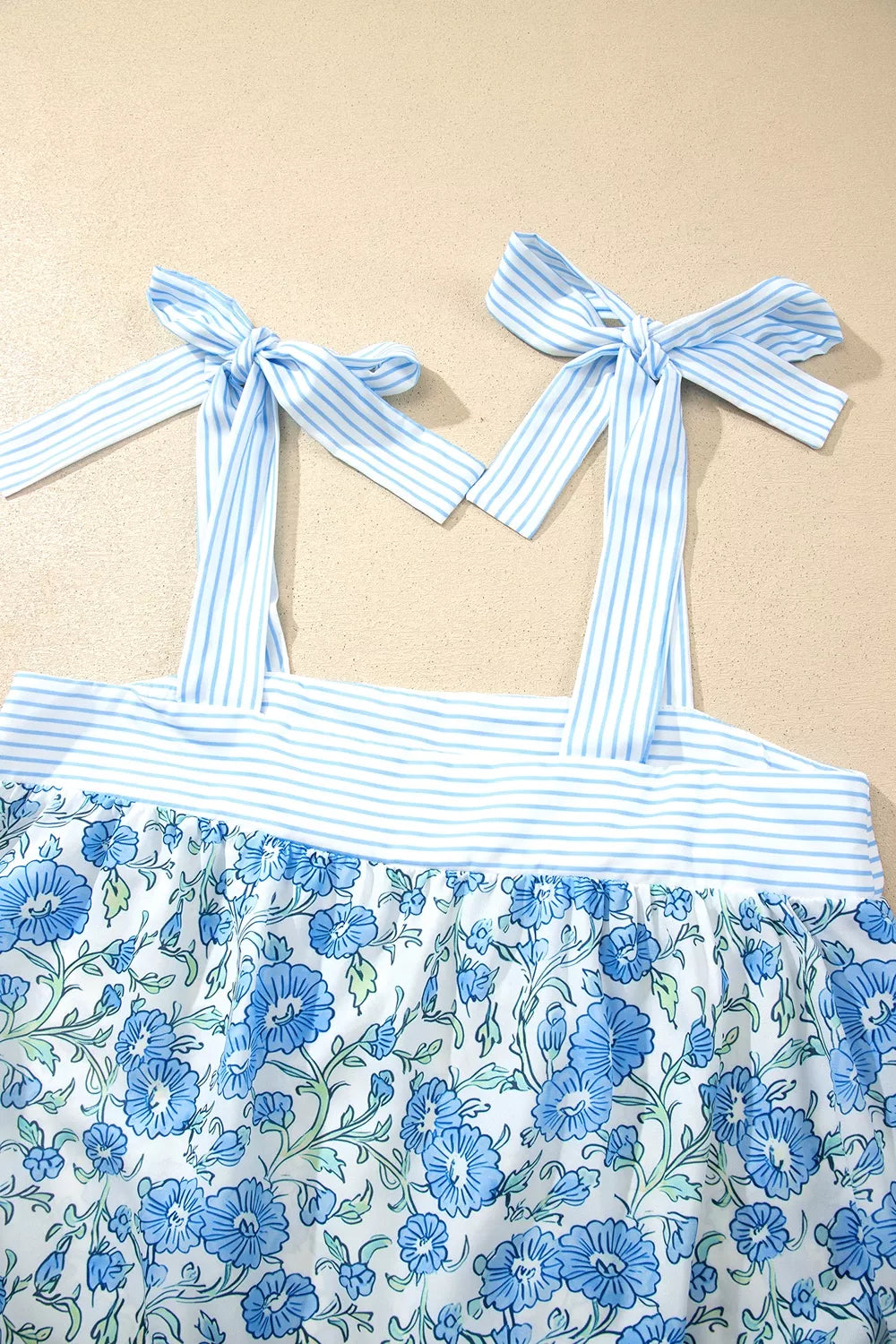 Blue floral print cami top with adjustable tie straps and striped trim, part of a loungewear set.