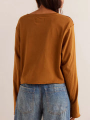 Caramel long sleeve crop top with raw hem detail, styled with denim jeans.