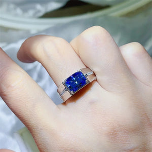 Men's blue gemstone signet ring with emerald cut moissanite and diamond accents.