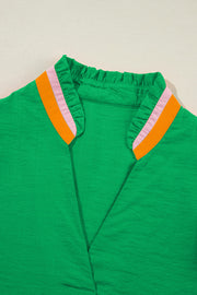 Green colorblock blouse with ruffled collar and orange and pink trim.