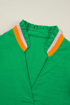Green colorblock blouse with ruffled collar and orange and pink trim.