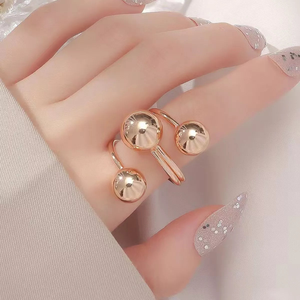 Gold multi-layered ball ring with adjustable alloy band.