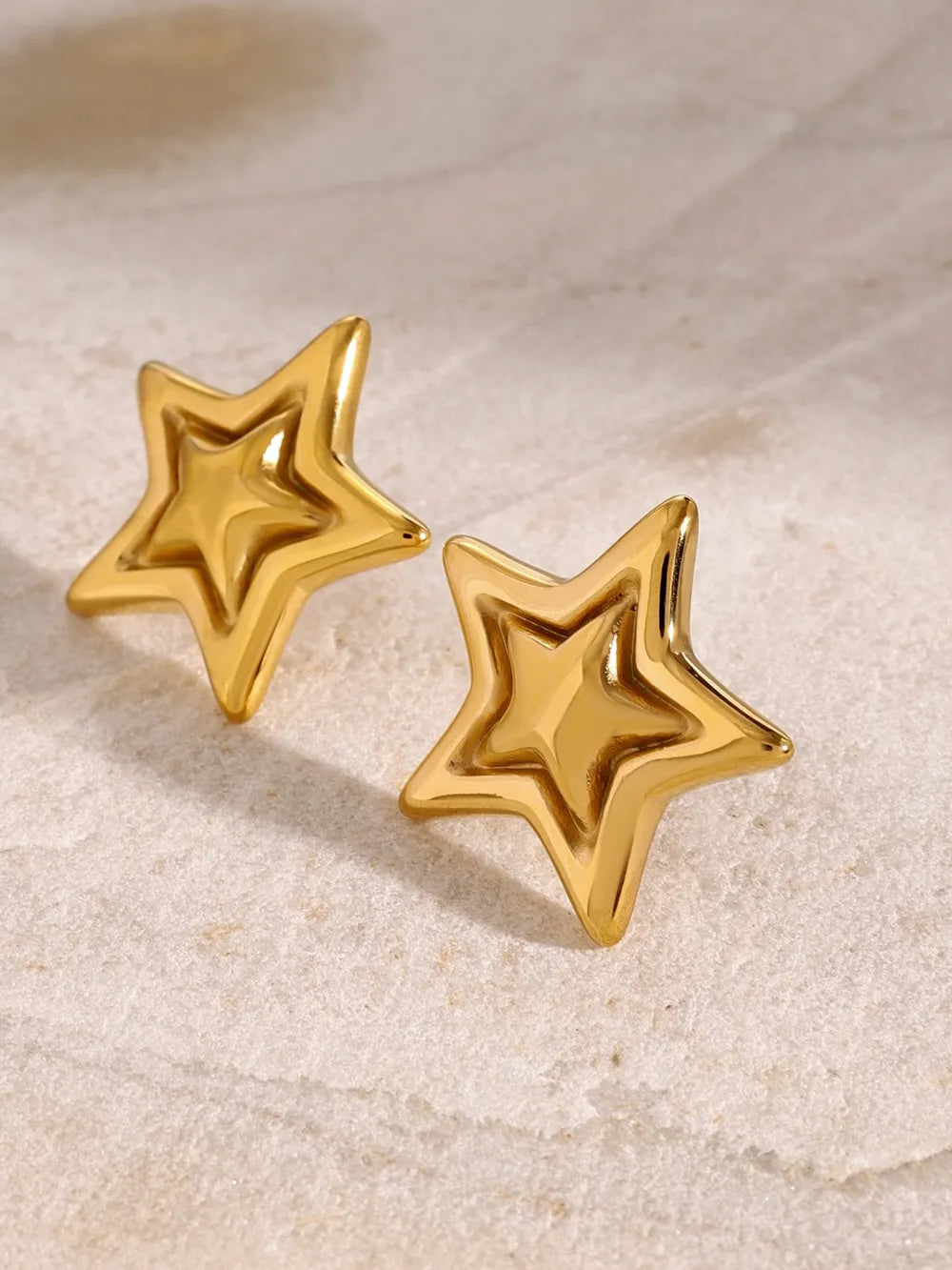Gold starburst stud earrings with a sculpted, dimensional design.