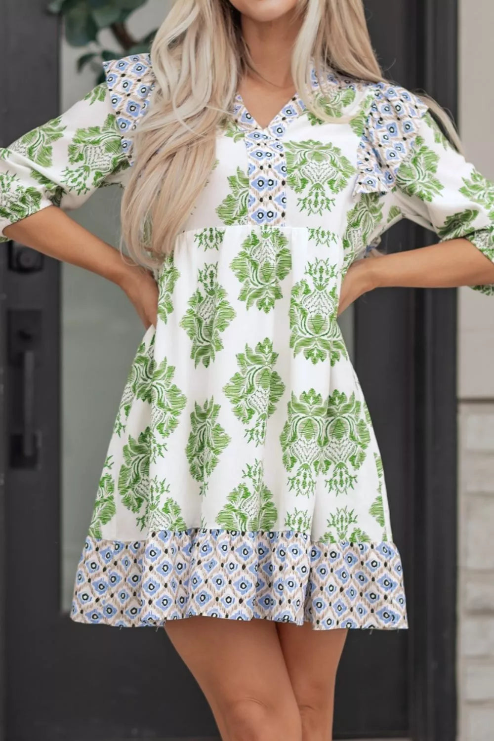 Mini dress with green floral print, ruffled neckline, and geometric hem.