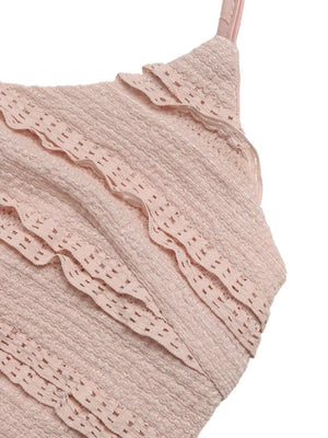 Pink textured halter romper with tiered ruffles and cutouts.