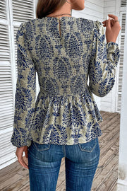 Navy damask print smocked peplum blouse with long sleeves and a keyhole back.