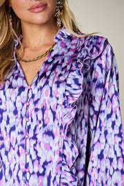 Blue purple blouse with abstract print, ruffle front, and button detail.