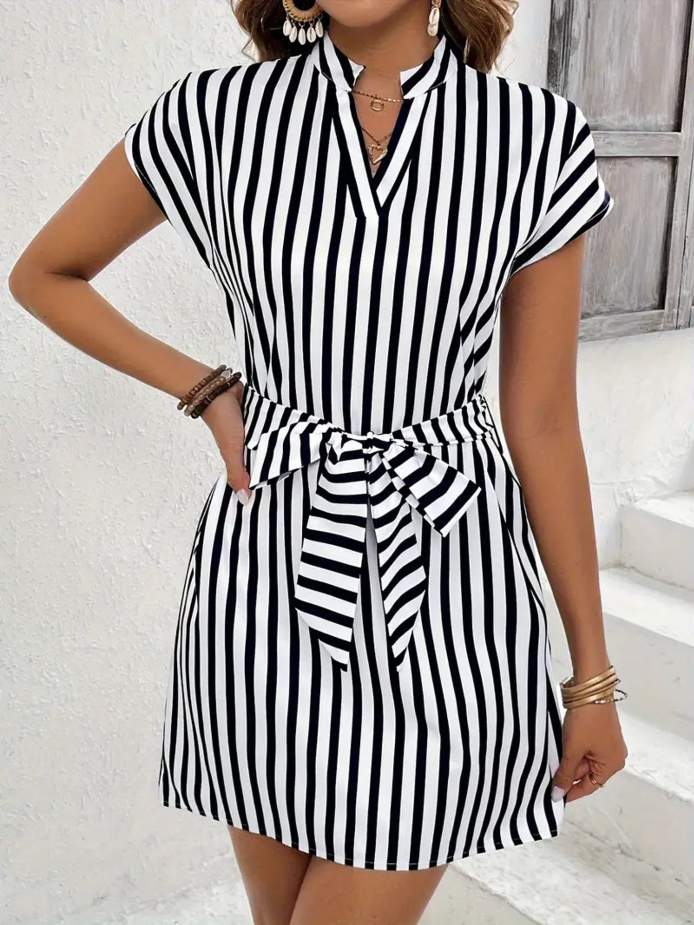 Chic black and white striped mini dress with V-neck, cap sleeves, and self-tie waist.