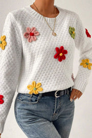 White knit sweater with colorful crochet floral embellishments and a textured pattern.